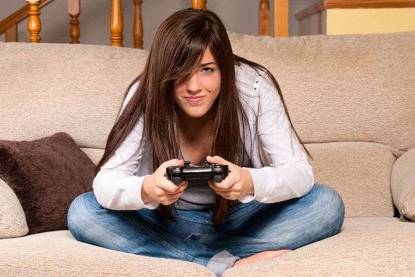 stock image Young female concentrating playing videogames on sofa at home