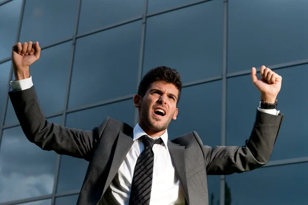 Fiatal sikeres üzletember, a modern épület háttérben egy gól ünneplése közben — Stock Fotó