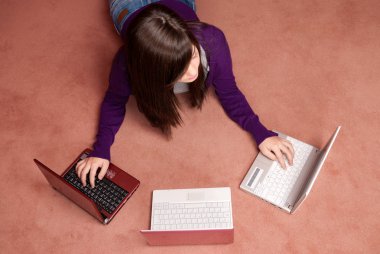 Young woman multitasking with three laptop lying on floor clipart