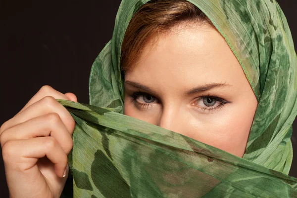 Wanita arab muda dengan kerudung yang menunjukkan matanya pada latar belakang abu-abu gelap — Stok Foto