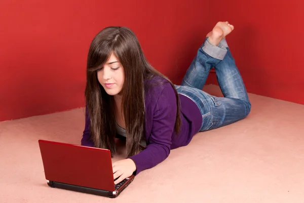 Νεαρή γυναίκα με φορητό υπολογιστή που βρίσκεται στον όροφο στο σπίτι — Φωτογραφία Αρχείου