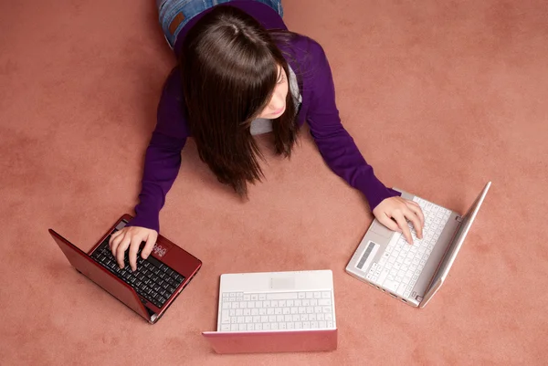 Jovem mulher multitarefa com três laptop deitado no chão — Fotografia de Stock