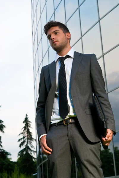 Young businessman looking to good future on modern building background — Stock Photo, Image