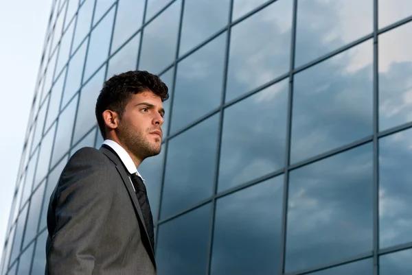 Joven hombre de negocios mirando hacia un buen futuro en el fondo del edificio moderno —  Fotos de Stock