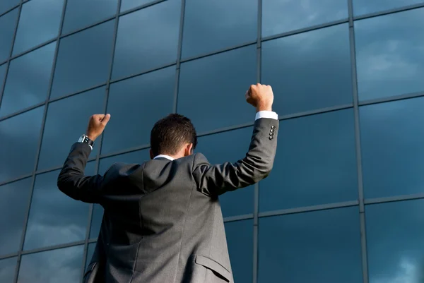 Ung framgångsrik affärsman firar ett mål på en modern byggnad bakgrunds — Stockfoto