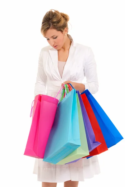 Jonge vrouw met boodschappentassen permanent op zoek naar zak geïsoleerd op wit — Stockfoto
