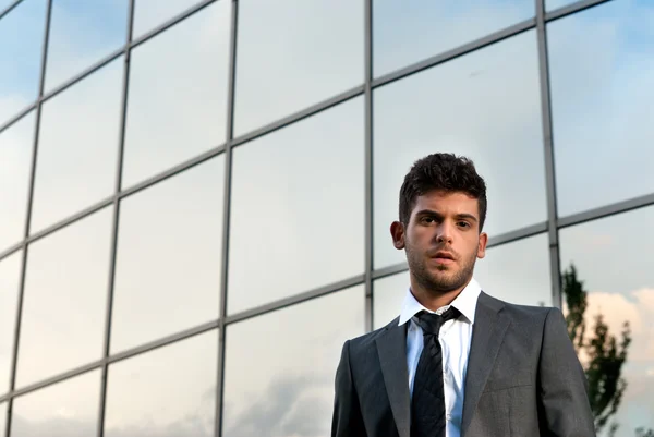 Young businessman looking to camera on modern building background — Stock Photo, Image