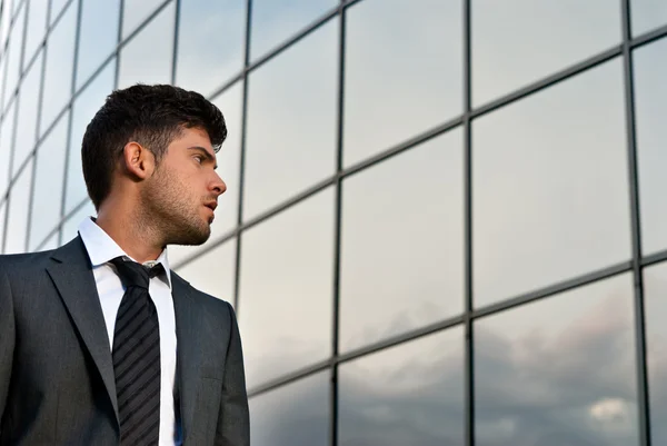 Giovane uomo d'affari alla ricerca di buone aspettative su sfondo edificio moderno — Foto Stock