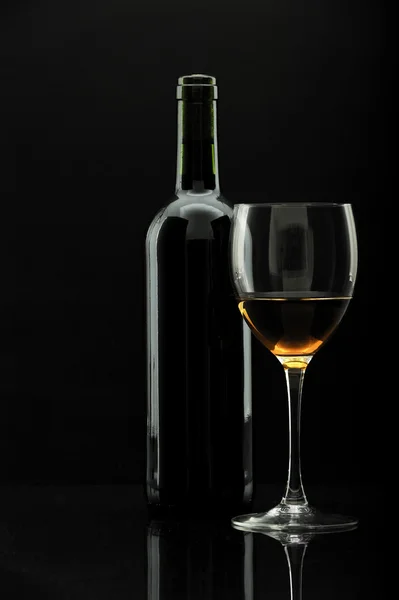 Бутылка вина и бокал вина поверх черного , — стоковое фото
