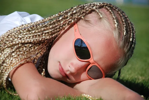 stock image The girl in pink glasses with the African plaits