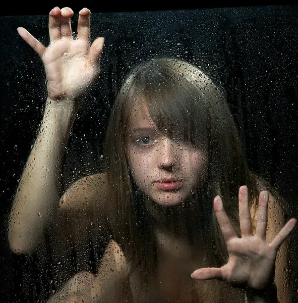 A menina atrás de vidro com gotas de chuva. Foco em gotas . — Fotografia de Stock