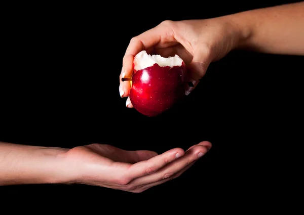 Mujer mano dando una manzana al hombre sobre fondo negro —  Fotos de Stock