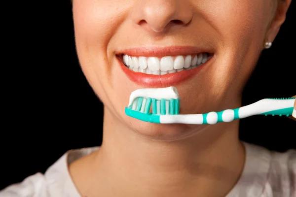 Kobieta zbliżenie zdrowy ząb ze szczoteczka do zębów na czarnym tle — Zdjęcie stockowe