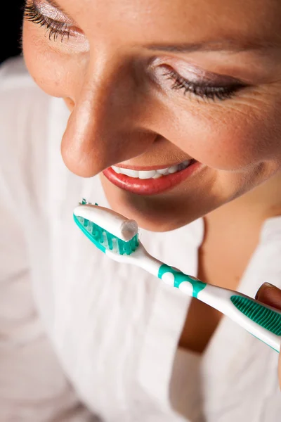 Kobieta zbliżenie zdrowy ząb ze szczoteczka do zębów na czarnym tle — Zdjęcie stockowe