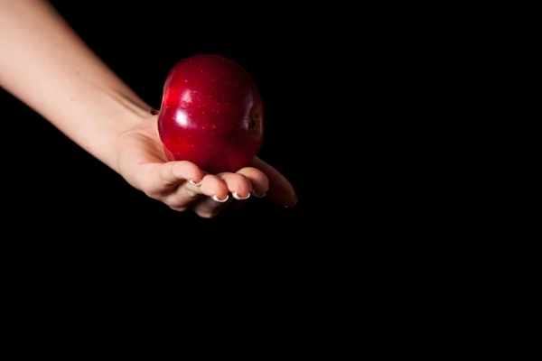 Adam siyah arka plan üzerine bir elma veren kadın eli — Stok fotoğraf