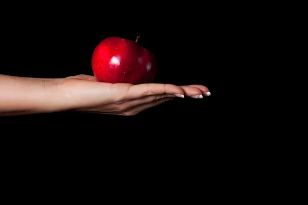Woman hand giving an apple to man on black background — Stock Photo, Image