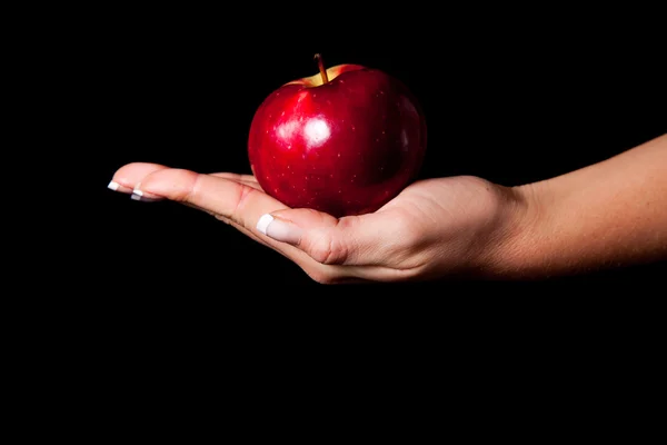 Frau reicht Mann einen Apfel auf schwarzem Hintergrund — Stockfoto