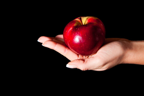 Женщина рука дарит яблоко мужчине на черном фоне
