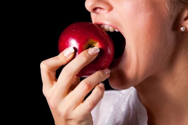 Жінка тримає червоне яблуко на чорному тлі — стокове фото
