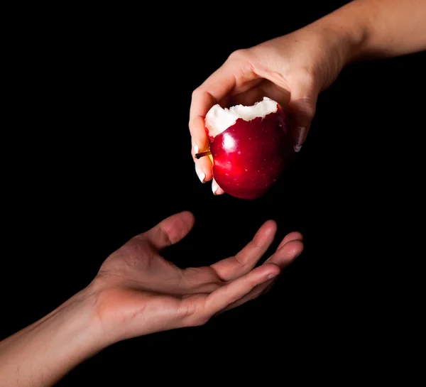 Mujer mano dando una manzana al hombre sobre fondo negro — Foto de Stock
