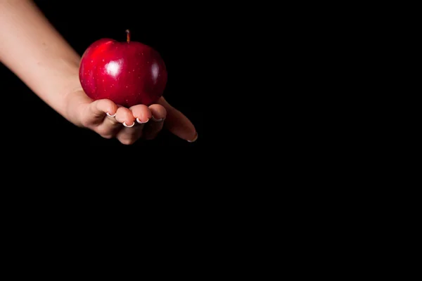 Kvinna hand ger ett äpple till mannen på svart bakgrund Stockfoto