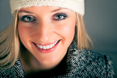 Portret van mooie blonde vrouw in warme kleren op blauwe achtergrond