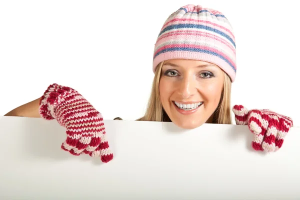 カラフルな帽子と手袋に分離されたホワイト ボードの後ろから覗いている女性 — ストック写真