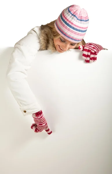 Mujer en sombrero colorido y guantes espiando desde detrás de la pizarra blanca aislado en — Foto de Stock