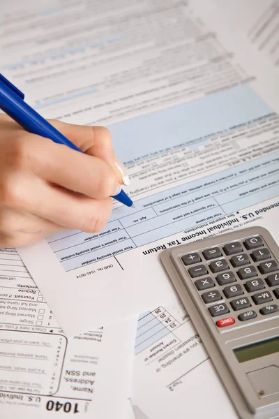 Femme remplissant à la main des formulaires d'impôt avec calculatrice — Photo