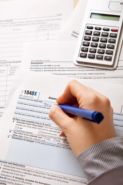 Kobieta strony wypełniając formularze podatkowe kalkulator — Zdjęcie stockowe