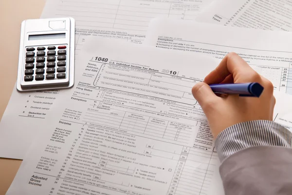 Ženská ruka vyplněním formuláře daně z příjmů s kalkulačkou — Stock fotografie