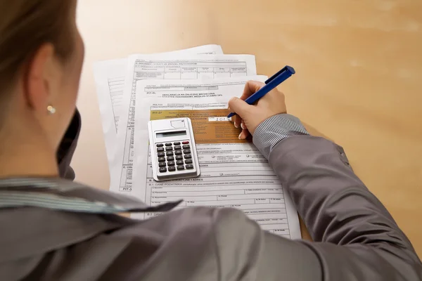 Woman hand filling income tax forms with calculator — Stock Photo, Image