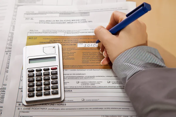 Vrouw hand invullen van inkomstenbelasting formulieren met calculator — Stockfoto