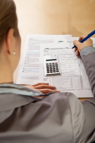 Рука жінки заповнює форми податку на прибуток калькулятором — стокове фото