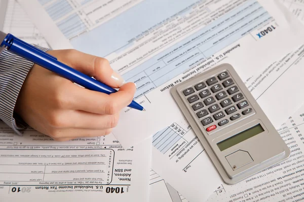 Woman hand filling income tax forms with calculator Stock Photo