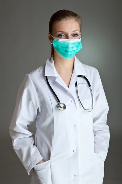 Médico mujer de uniforme con estetoscopio en gris neutro — Foto de Stock