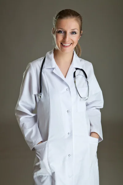 Γυναίκα ιατρός με τη στολή με το στηθοσκόπιο σε ουδέτερο γκρι — Φωτογραφία Αρχείου