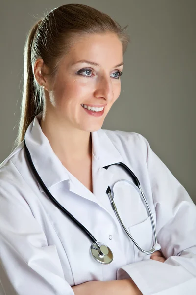 Женщина-врач в форме со стетоскопом на нейтральном сером — стоковое фото