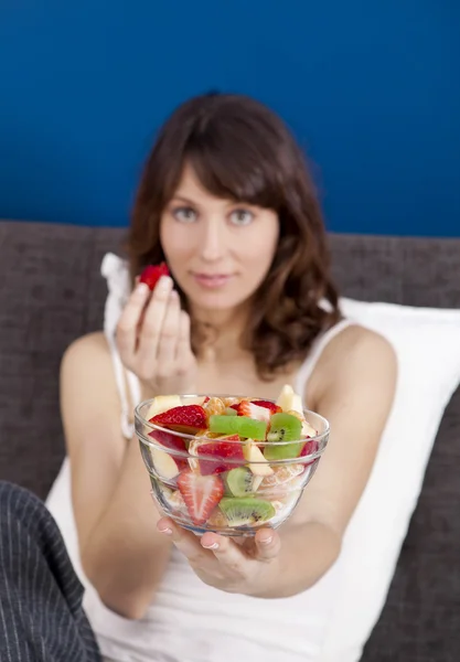 Flicka på bed äta frukter — Stockfoto