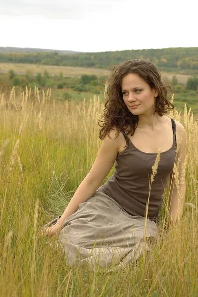 Kobieta siedzi w polu — Zdjęcie stockowe