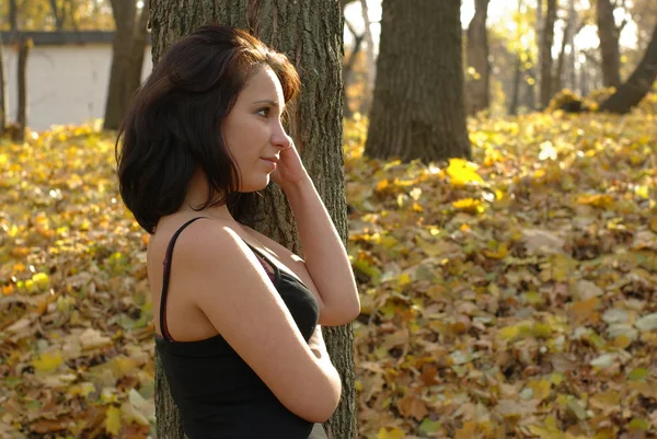 Задумчивая девушка в осеннем лесу — стоковое фото