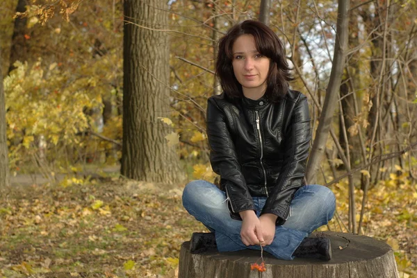 Flicka sitter på en stubbe — Stockfoto