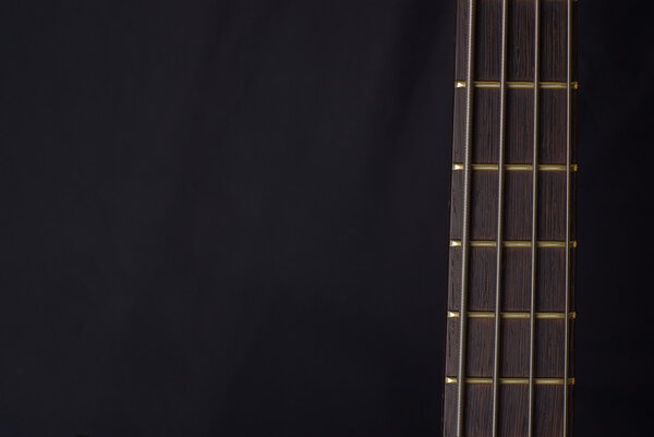 Neck of a bass guitar on the black background