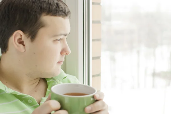 若い男が 窓辺にお茶を飲む — ストック写真