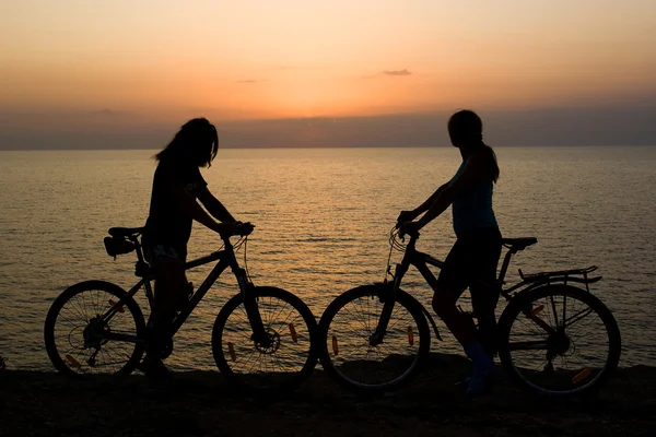 Couple avec vélos regardant coucher de soleil . — Photo