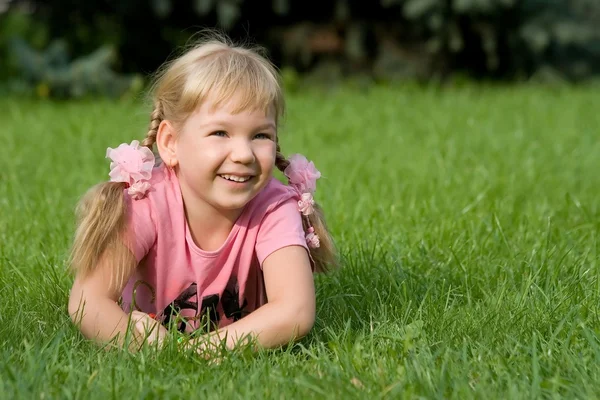 Schattig klein meisje in gras. — Stockfoto