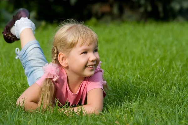 Schattig klein meisje in gras. — Stockfoto