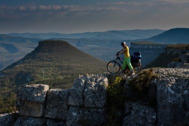 Girl with bike in mountains. clipart