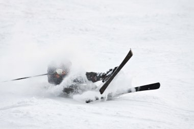 Man riding on skis fall down, he could break something. clipart