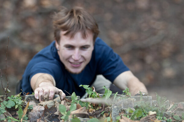 Rock-climber making his way to the top, focus on hand.